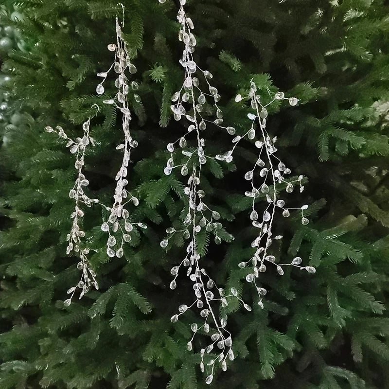 A set of acrylic crystal pendant drops for Christmas tree decor hanging from a green fir branch.