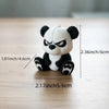 A cute angry panda figurine with black and white fur sitting on a wooden surface.