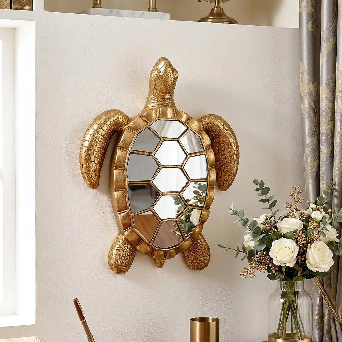 A golden sea turtle resin wall decor mirror mounted on a white wall.