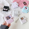 A hand holds a pink mini snap button photo album featuring K-Pop idols and ID cards.