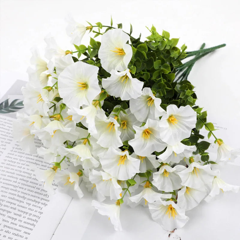 A bouquet of white artificial silk cloth flowers with green foliage.