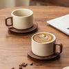 A ceramic coffee cup and saucer set with latte art resting on a wooden table.