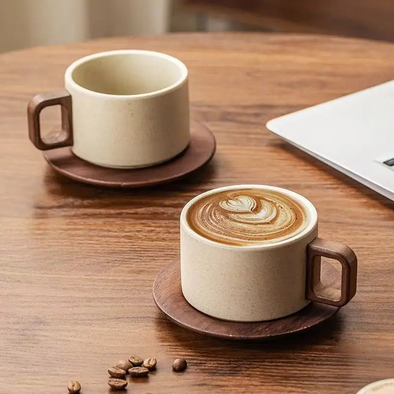 A ceramic coffee cup and saucer set with latte art resting on a wooden table.