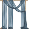 A set of two sheer blue chiffon fabric panels draped over a wooden arch for wedding decor.