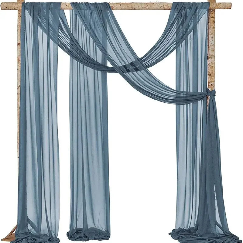 A set of two sheer blue chiffon fabric panels draped over a wooden arch for wedding decor.