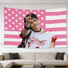 A portrait of Hyunjin making a finger sign against a pink American flag tapestry.