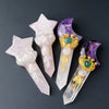 A collection of natural crystal moon and star scepter wands in pink and purple hues.