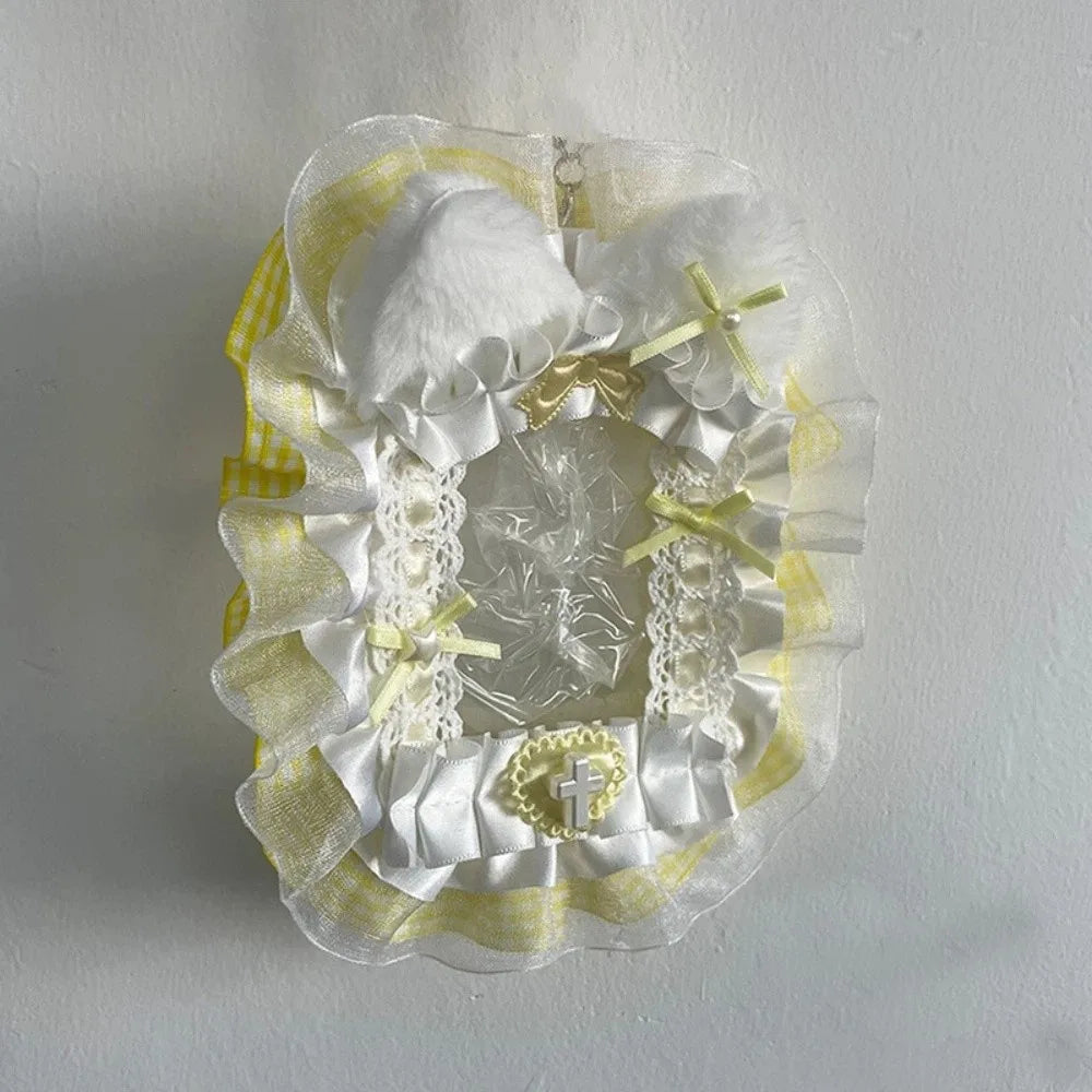 Porte-cartes clair décoré de rubans blancs et jaunes et de pompons blancs moelleux.