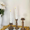 A vintage resin wall sconce candle holder with a white candle displayed on a gold-framed tray.