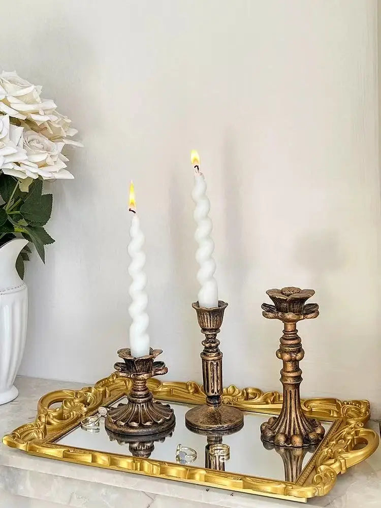 A vintage resin wall sconce candle holder with a white candle displayed on a gold-framed tray.