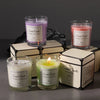 A collection of scented candles in glass jars and boxes featuring purple, pink, and green wax.