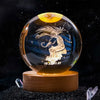 A spherical crystal ball with a dark blue background featuring a white silhouette of a mythical creature and engraved date.