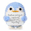 A light blue crocheted penguin doll with a white sign that reads Positive penguin I may be a tiny penguin but I believe in yo