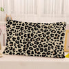 A decorative pillow cover featuring a black and tan leopard print on a white background.
