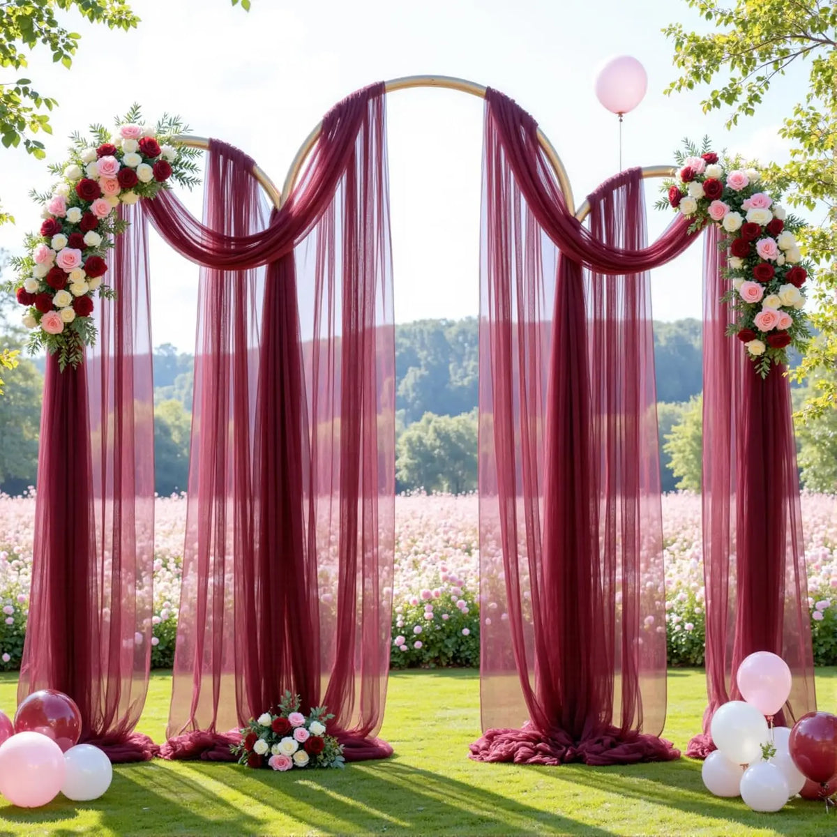 A pink and red tulle backdrop with draped curtains and floral arrangements for an elegant event.