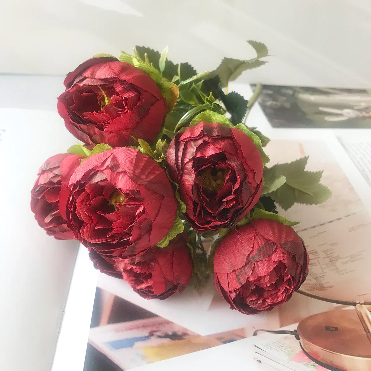 A bouquet of deep red silk rose and peony artificial flowers arranged for home or event decor.