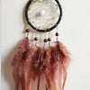 A dream catcher pendant featuring a crystal mirror, beads, and long, reddish-brown feathers.