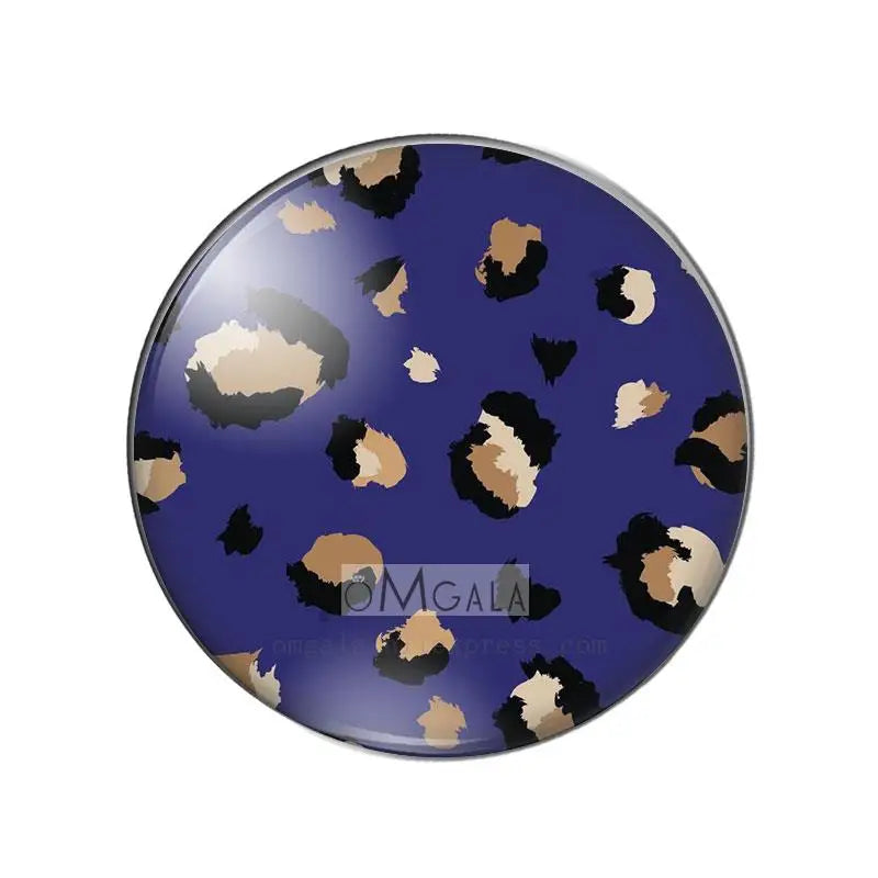 A round glass cabochon with a dark blue background featuring irregular leopard print patterns in black and tan.