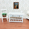 A white wooden table with drawers and a wooden chair sits in front of a framed art print featuring two cats under a starry ni