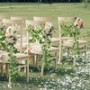 Wedding ceremony chairs decorated with artificial ivy vine garlands and floral accents on a grassy lawn