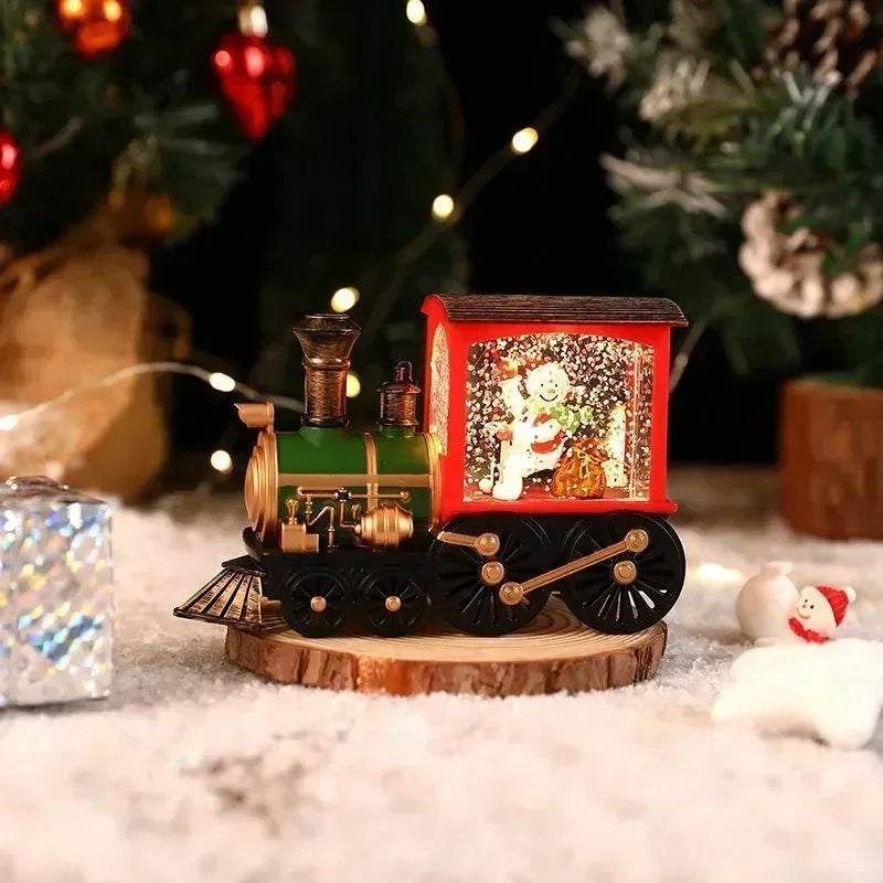 A vintage red and green Christmas train music box with LED lights sits on a wooden surface surrounded by festive greenery.