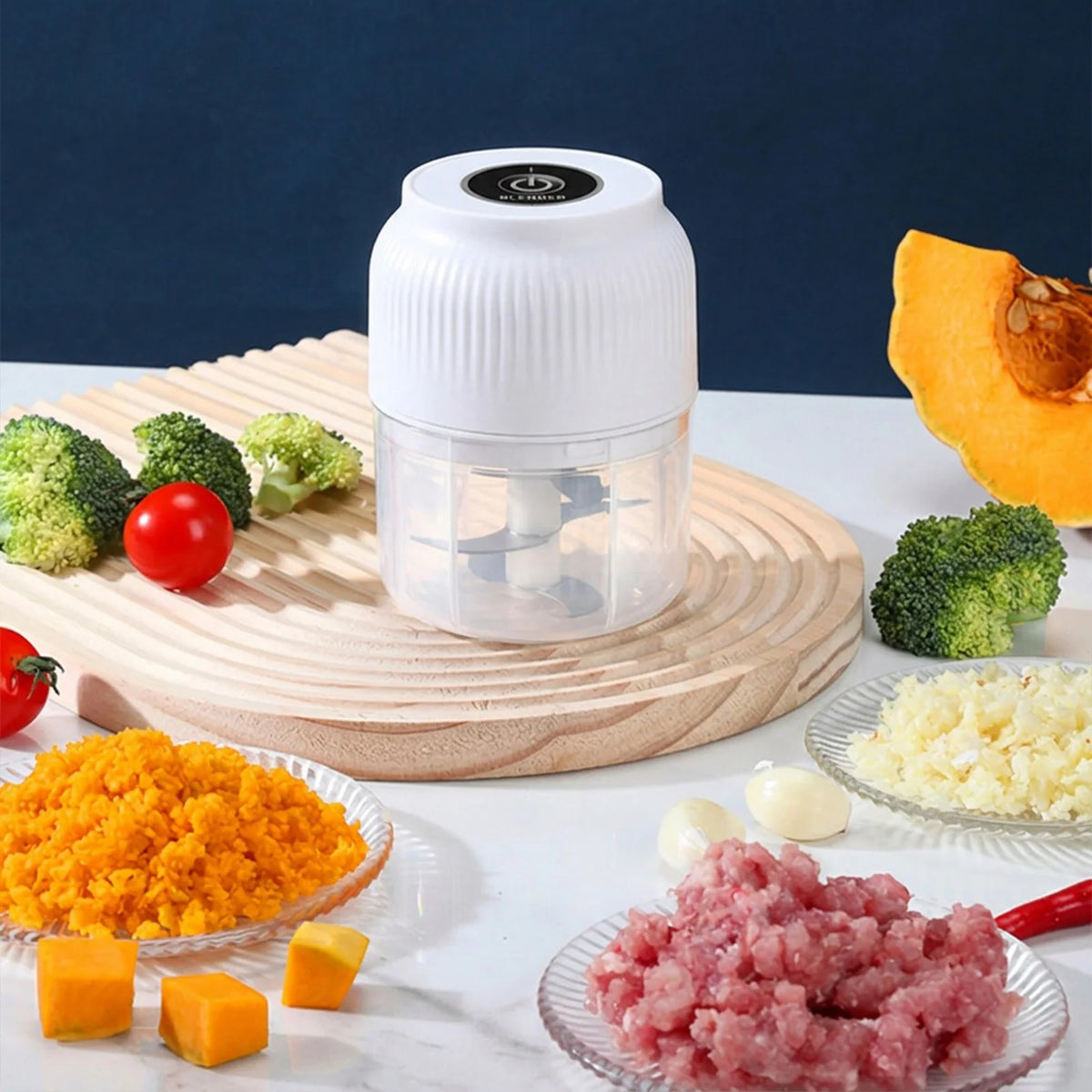 A white portable electric mini food chopper jar filled with chopped vegetables and garlic, placed on a wooden cutting board.
