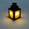 A black pixel style night light lantern with an orange glow sits on a light surface.