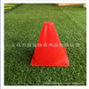 A bright red, cone-shaped birthday racing car party decoration is placed on green artificial turf.