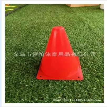 A bright red, cone-shaped birthday racing car party decoration is placed on green artificial turf.