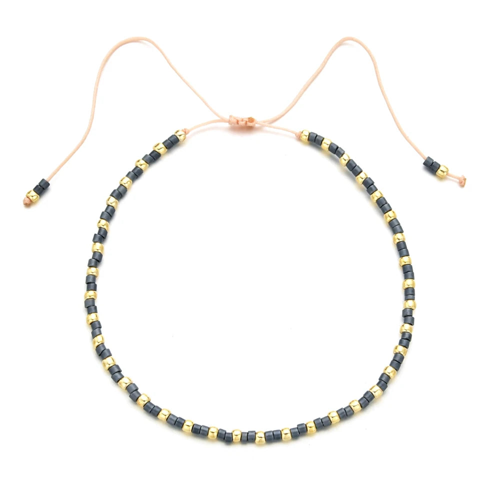 Handmade boho glass bead bracelet with adjustable cord featuring black and gold beads.
