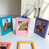 Three magnetic photo frames in teal, pink, and purple are displayed on a white surface.