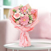 A bouquet of handcrafted crochet tulip flowers in various shades of pink and green, wrapped in pink paper.