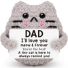 A handcrafted gray crochet cat doll with black stripes and pink accents, holding a card that says I'll love you dad.