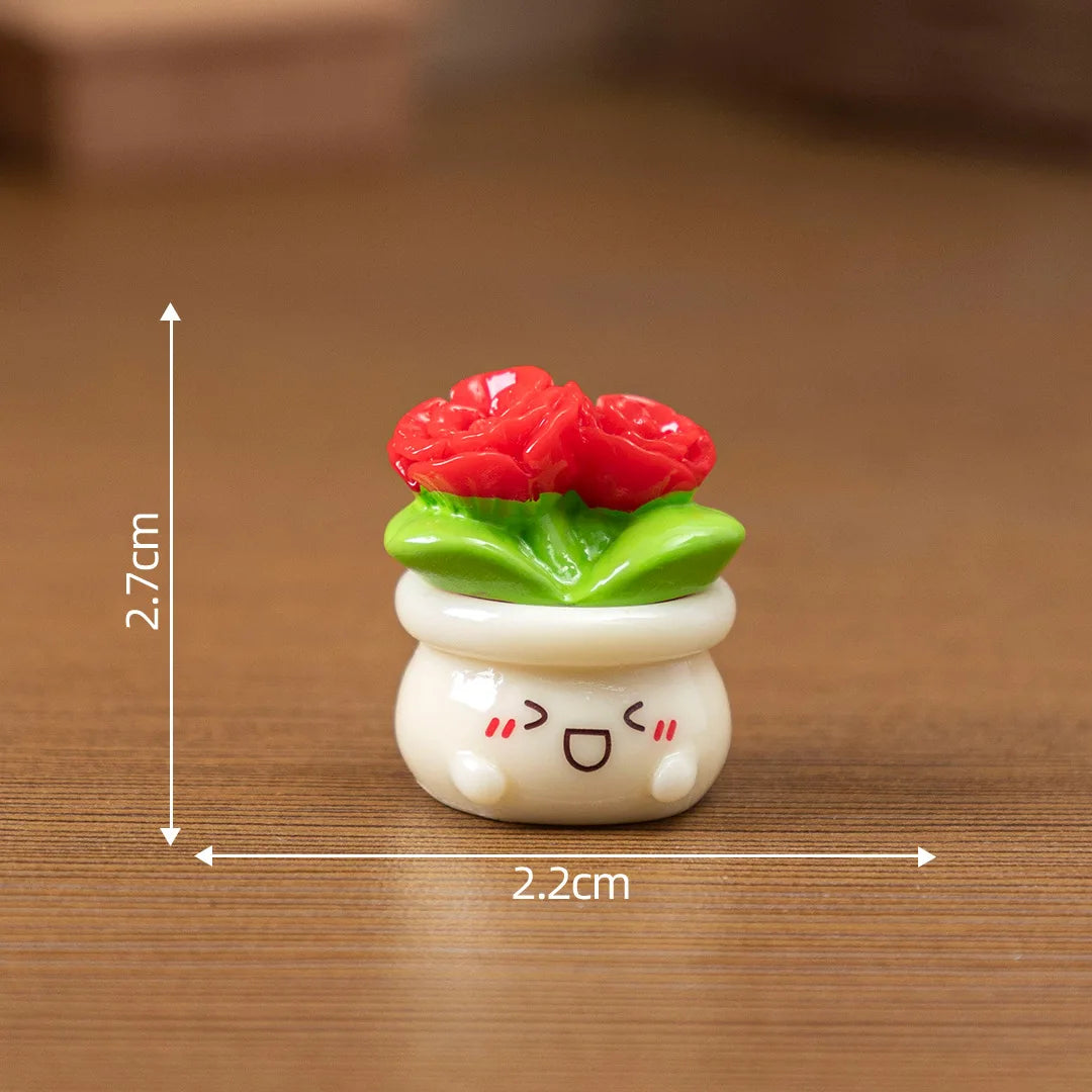 A small resin charm depicting a red rose growing from a green leaf, sitting atop a white, smiling, round base.