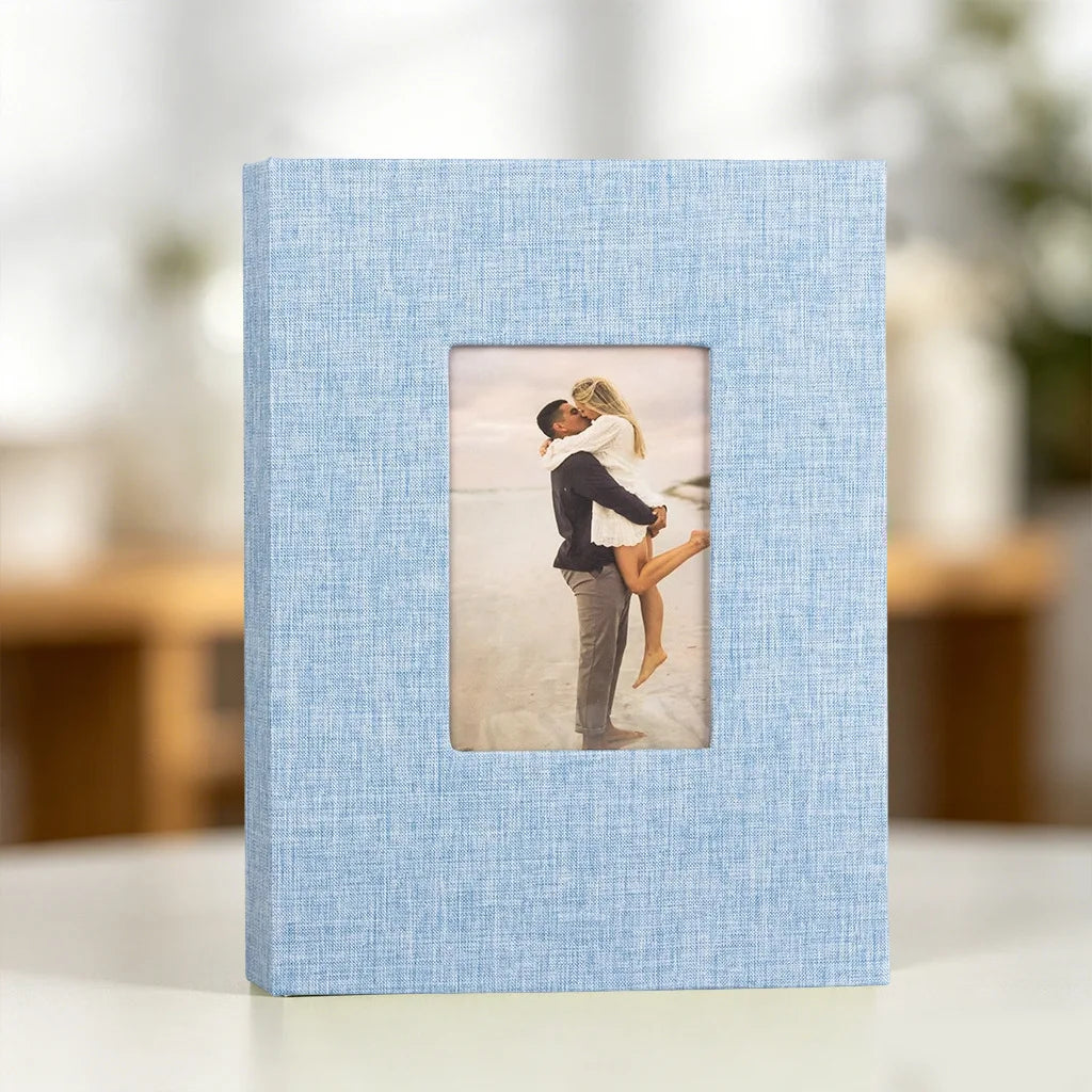 A light blue linen photo album with a square display window featuring a black and white photo of a couple embracing.
