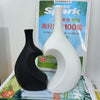 A black and white modern heart-shaped ceramic vase displayed in front of a product sign.
