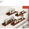 A set of natural wood floating shelves mounted on a white wall displaying various decorative items.