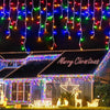 Christmas lights draped like waterfalls across a house facade decorated for the holiday season.