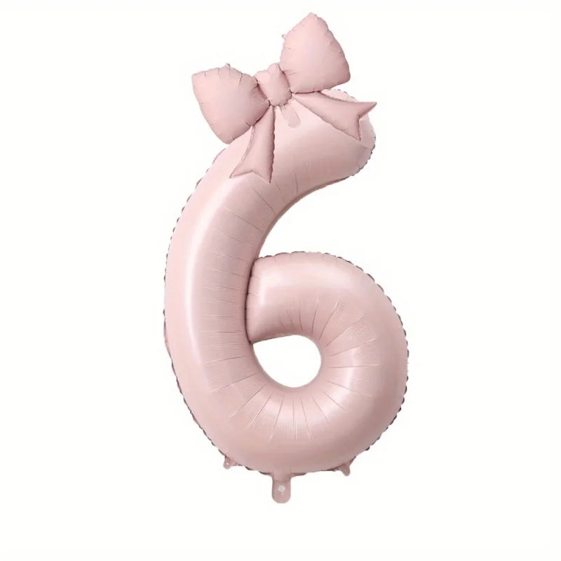 A large pink foil number balloon shaped like the number 6 with a bow.