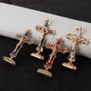 A set of four metal crucifix desk crosses with self-adhesive bases displayed on a dark surface.