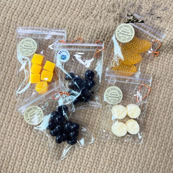 Packaged handmade fruit keychains in clear plastic bags featuring yellow and black fruits