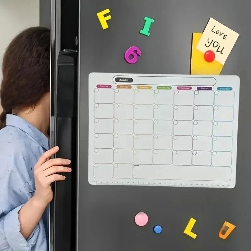 A close-up of a magnetic fridge planner with a monthly grid and colorful sticky notes on a dark gray refrigerator.