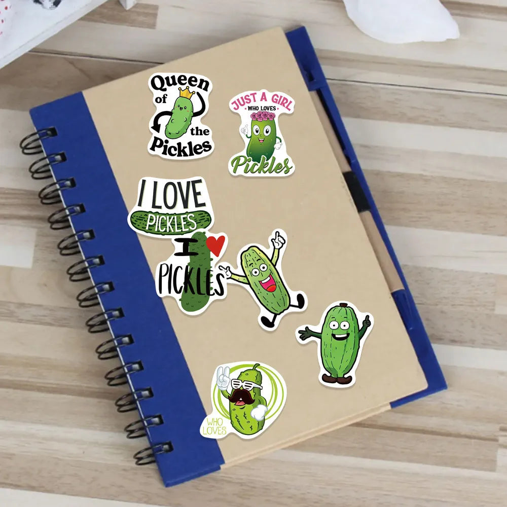 A notebook decorated with cartoon pickle stickers featuring text like I love pickles and Queen of the Pickles.