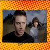 A promotional image featuring two men, one with short hair and another with longer hair, set against a natural outdoor backgr