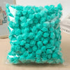 A clear plastic bag filled with bright turquoise artificial rose foam flowers for DIY decoration.
