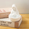 White resin statue of the Virgin Mary with a halo, displayed on a stack of books.