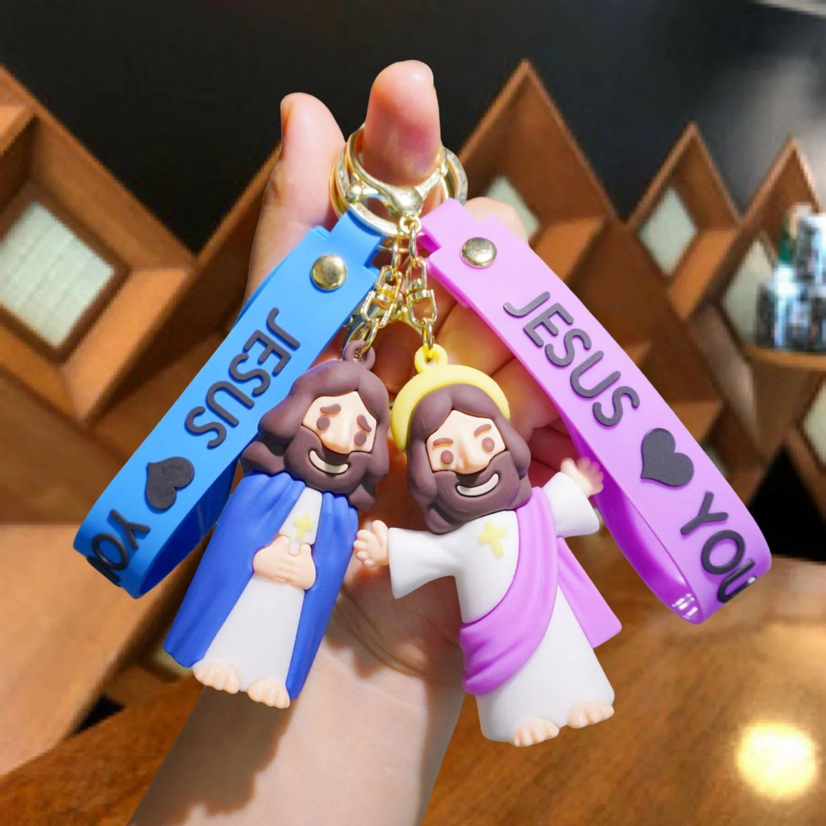 A hand holds a silicone keychain featuring Jesus with a colorful strap and gold ring.