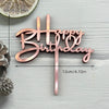 A rose gold acrylic birthday cake topper set spelling out Happy Birthday