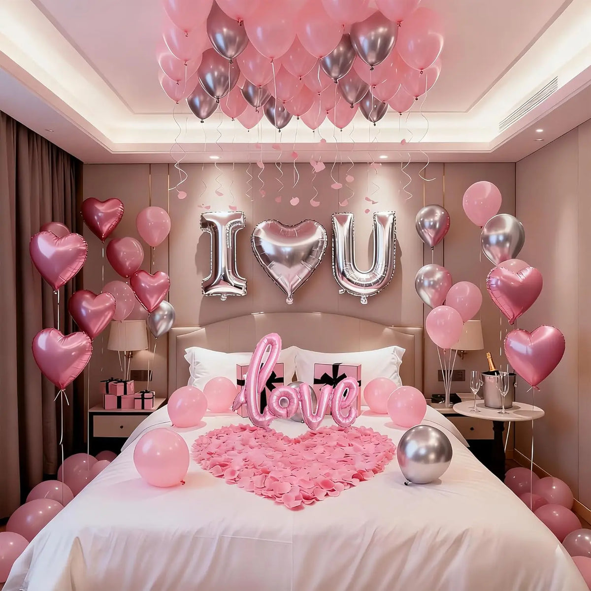 Décoration de ballons en forme de cœur rose et argenté sur un lit avec des rideaux drapés.
