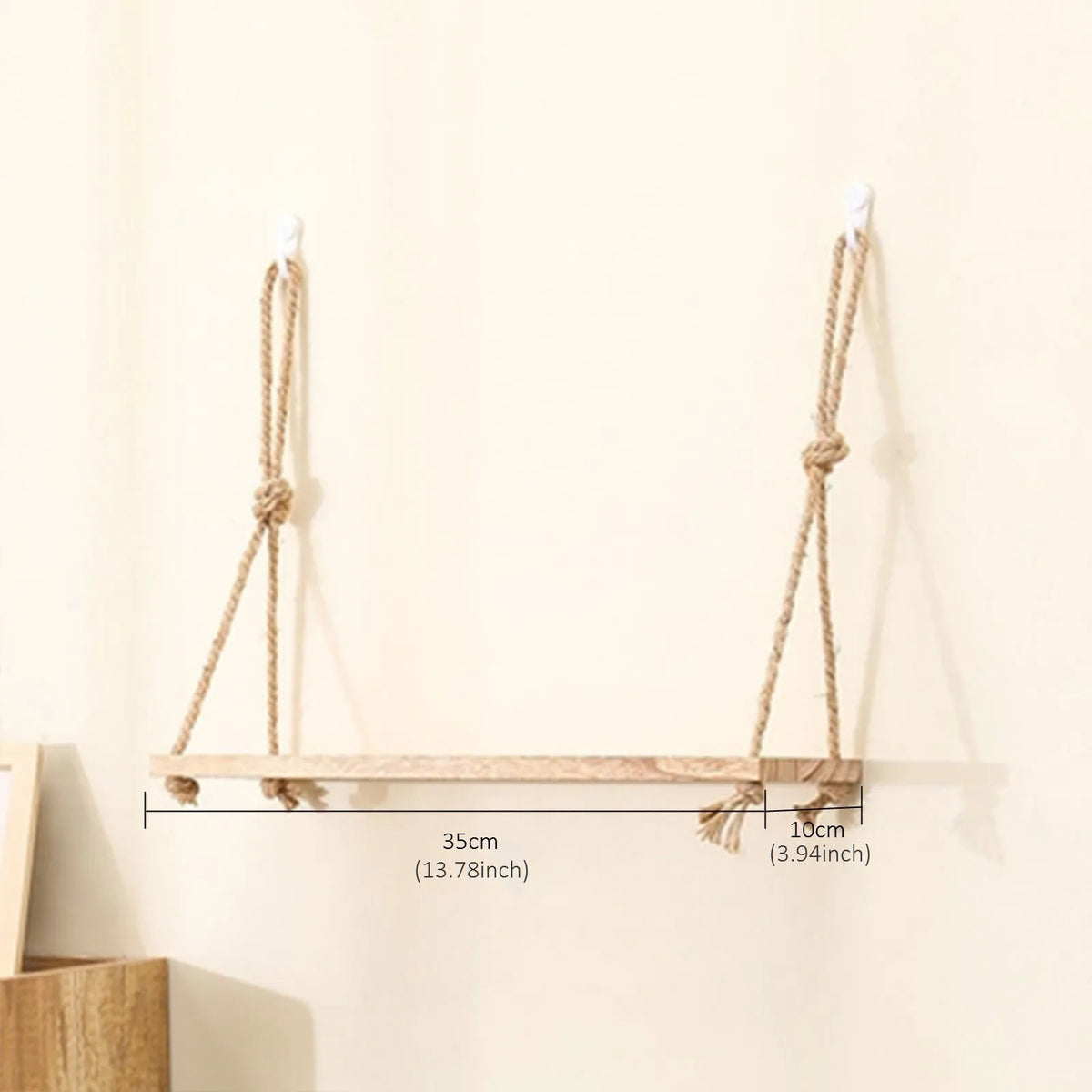 A rustic floating wooden storage shelf with natural twine hangers mounted on a light-colored wall.